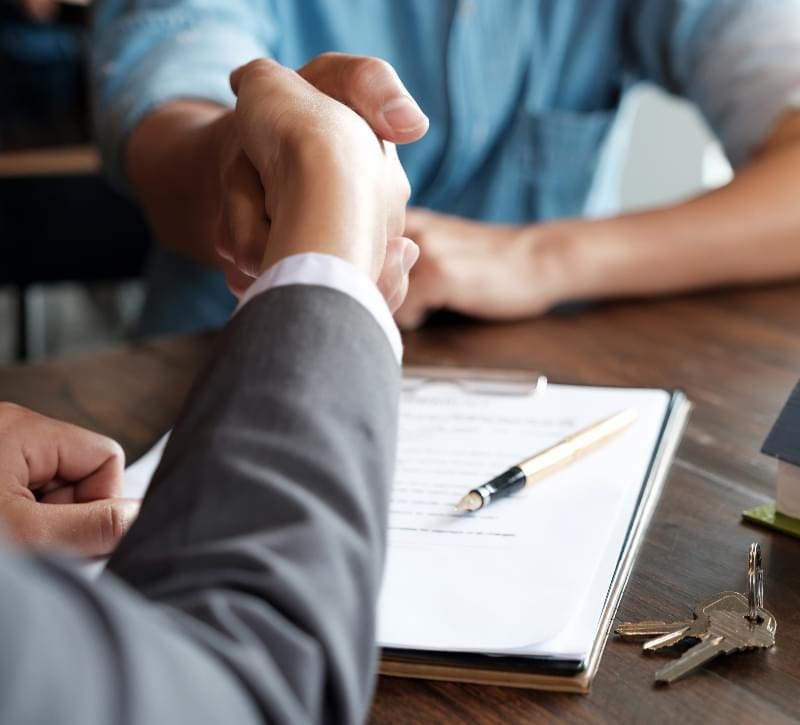 A real estate agent shaking hands with their client at closing.