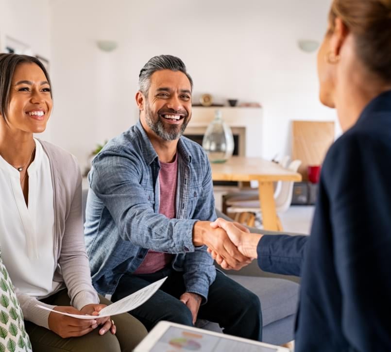 A couple shaking hands with their real estate agent.